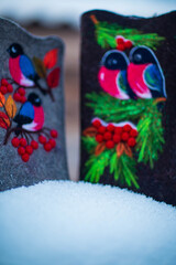 embroidered felt boots taken on a winter evening against the background of snow, bushes and a village house