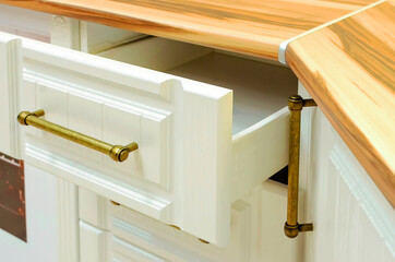 Opened white drawer in a kitchen cabinet, close-up.