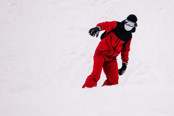 Naklejka premium A guy in a red jumpsuit eating freeride on a snowboard on a snowy slope
