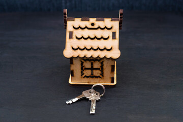 model of a wooden house with keys on a black background.