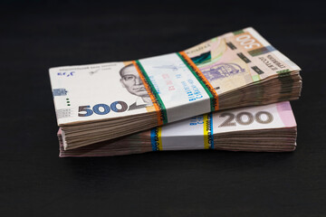 bundles of hryvnia on a black wooden background. Ukrainian money in denominations of 200 and 500 hryvnia.