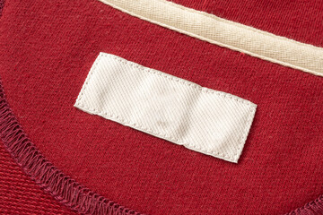 Blank white laundry care clothes label on red fabric texture background