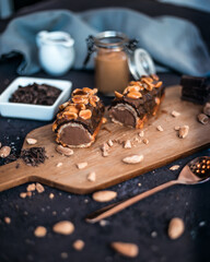 Traditional French dessert eclair with dark chocolate and peanuts in a composition on a wooden...