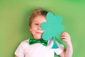 Portrait Cute Child boy holding paper clover shamrock on green background.
Irish St. Patrick's Day 