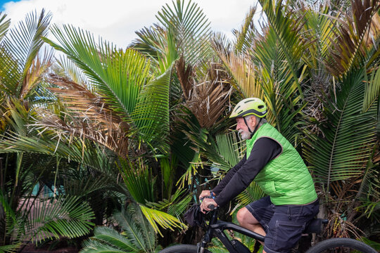 Senior adult man enjoying bike ride in outdoor tropical place. Peaceful retiree enjoying his free time