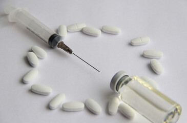 Syringes with a vaccine and different tablets on a light background