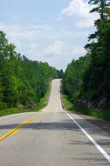 straight empty road with yellow line leading up hill 