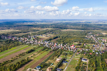 Fototapeta na wymiar Luftaufnahme über Dorf und Wälder bei blauen Himmel mit Wolken