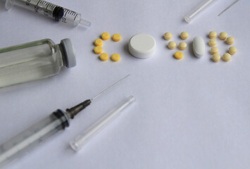 The word covid 19 is laid out from different tablets with a syringe and a vaccine
