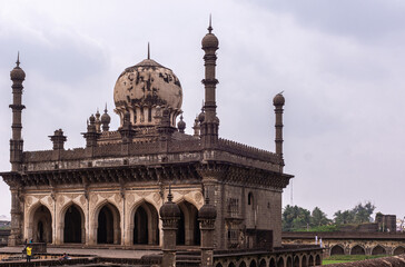 Vijayapura, Karnataka, India - November 8, 2013: Ibrahim Rauza Mosque is brown building with dome and minarets under light blue cloudscape. 