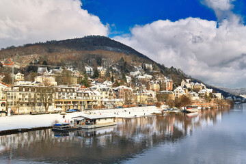 Fototapeta na wymiar Heidelberg, Germany. View on Odenwald forest hill called Heiligenberg with historical mansions covered in snow and neckar river. View from Theodor Heuss bridge on sunny winter day