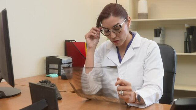 Latin female doctor examines chest x-ray of patientC348:D354 then shakes her head no give a bad prognosis
