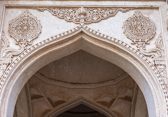 Vijayapura, Karnataka, India - November 8, 2013: Closeup of white stone arch with extenseive non-figurative sculptures on facade of Ibrahim Rauza mosque.