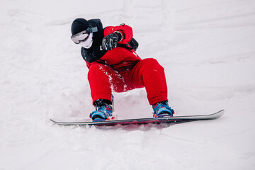 Naklejka premium A guy in a red jumpsuit eating freeride on a snowboard on a snowy slope