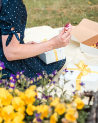 Young woman treat herself with traditional French dessert eclairs or profiteroles. A young couple having a picnic in summer day