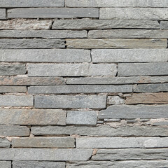 rough grey slate stone wall closeup, textured pattern background