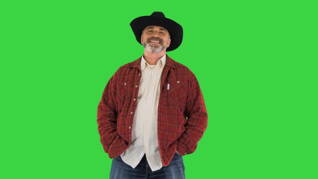 Elderly caucasian man farmer agronomist in cowboy hat smiling to camera on a Green Screen, Chroma Key.