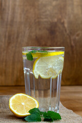 mojito cocktail with lime.summer drinks. close-up glass of lemonade with lemon and fresh leafs mint. homemade cold refreshing drink or water with ice with sackcloth on rustic wood background.