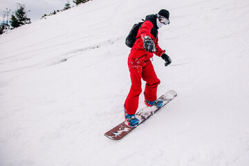 Naklejka premium A guy in a red jumpsuit eating freeride on a snowboard on a snowy slope