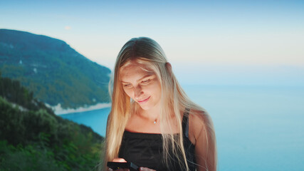 Woman using smartphone with ocean in the background. Vacations in warm countries.