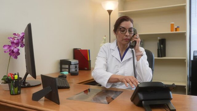 Female Latin doctor reviews patient x-ray and calls colleague to confer