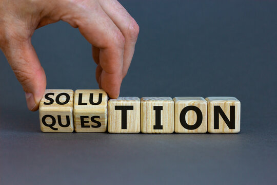Question and solution symbol. Businessman turns wooden cubes and changes the word 'question' to 'solution'. Beautiful grey table, grey background, copy space. Business, question and solution concept.