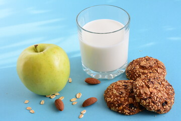 oat cookies with glass of milk and apple on the sunshine background