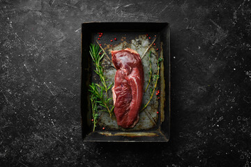 Raw fresh duck fillet with rosemary and spices. On a black background. Top view.