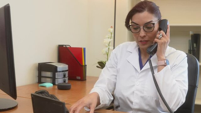 Close up of attractive Latin doctor on phone with colleague discussing patient chest Xray.