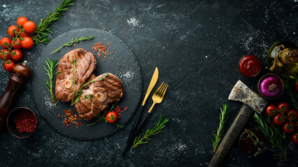 Grilled lamb steak with spices and rosemary. Barbecue meat. Top view. Flat lay top view on black stone cutting table.