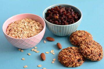 oat cookies with bowls of oatmeal and raisin on the blue background