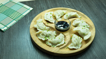homemade dumplings on a wooden plank with soy sauce 