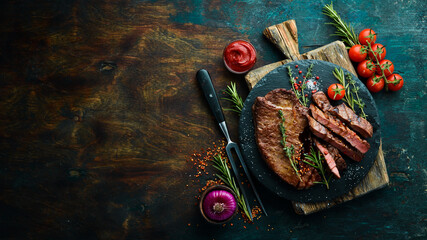 Juicy veal steak with spices, thyme and rosemary. Top view. Flat lay top view on black stone cutting table.