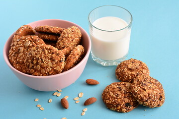 bowl with oat cookies and glass of milk on the blue background