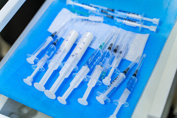 Many syringes on a blue sheet in operation room. Different sizes of syringes ready to be used. View...