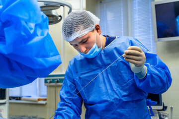 Experiensed doctor in the process of complex operation with futuristic equipment. Medic in blue...