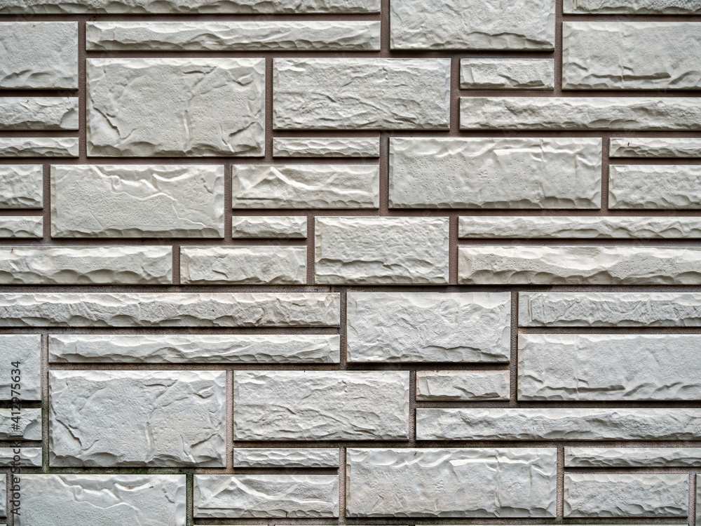 Poster decorative gray plaster on the wall, which is lined with bricks of different sizes. bricks and uneve