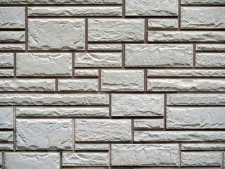 Decorative gray plaster on the wall, which is lined with bricks of different sizes. Bricks and uneven plaster surfaces create an interesting stone backdrop.