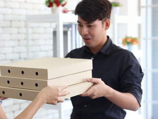 Hands deliver the goods to the recipient customer. Young man receiving delivery pizza box, shipping and courier delivery services express concept.