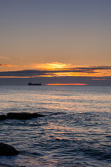 Fototapeta na wymiar Sunrise by the Black Sea with big transporter ship silhouette