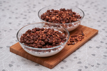 Natural yogurt, cereal and granola in glass bowls on wooden board. Healthy breakfast for someone special concept