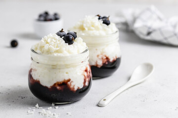 Traditional rice pudding with berry jam in glass jars. Space for text.