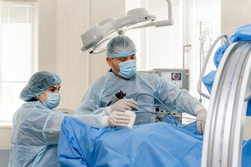 Group of surgeons in operating room with surgery equipment in hands. Medical modern room background. Selective focus.