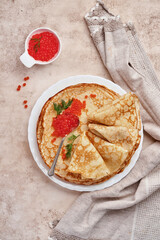 Crepes, thin pancakes, Russian pancakes with red caviar on gray plate. Marble background. Copy space. Top view.