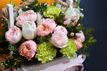 a young girl in a mustard dress holds in her hands a beautiful composition of flowers in a box created by a florist. the concept of a pleasant sale for a holiday.