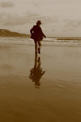 Man with hat running on the sandy beach