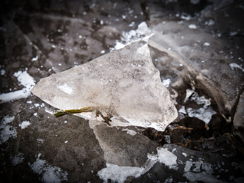 Teleobjektiv Nahaufnahme eines St&uuml;cks Eis im Winter, das aus einer Eisfl&auml;che herausgebrochen ist, Makro mit Vignetteneffekt