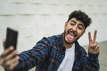 Shallow focus shot of a handsome happy European guy taking selfies by pho