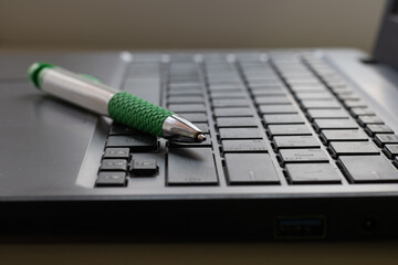 Laptop keyboard black on gray background with a pen on it. Close-up of laptop keyboard.