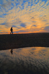 Silhouette of man walking on beach at the sunset